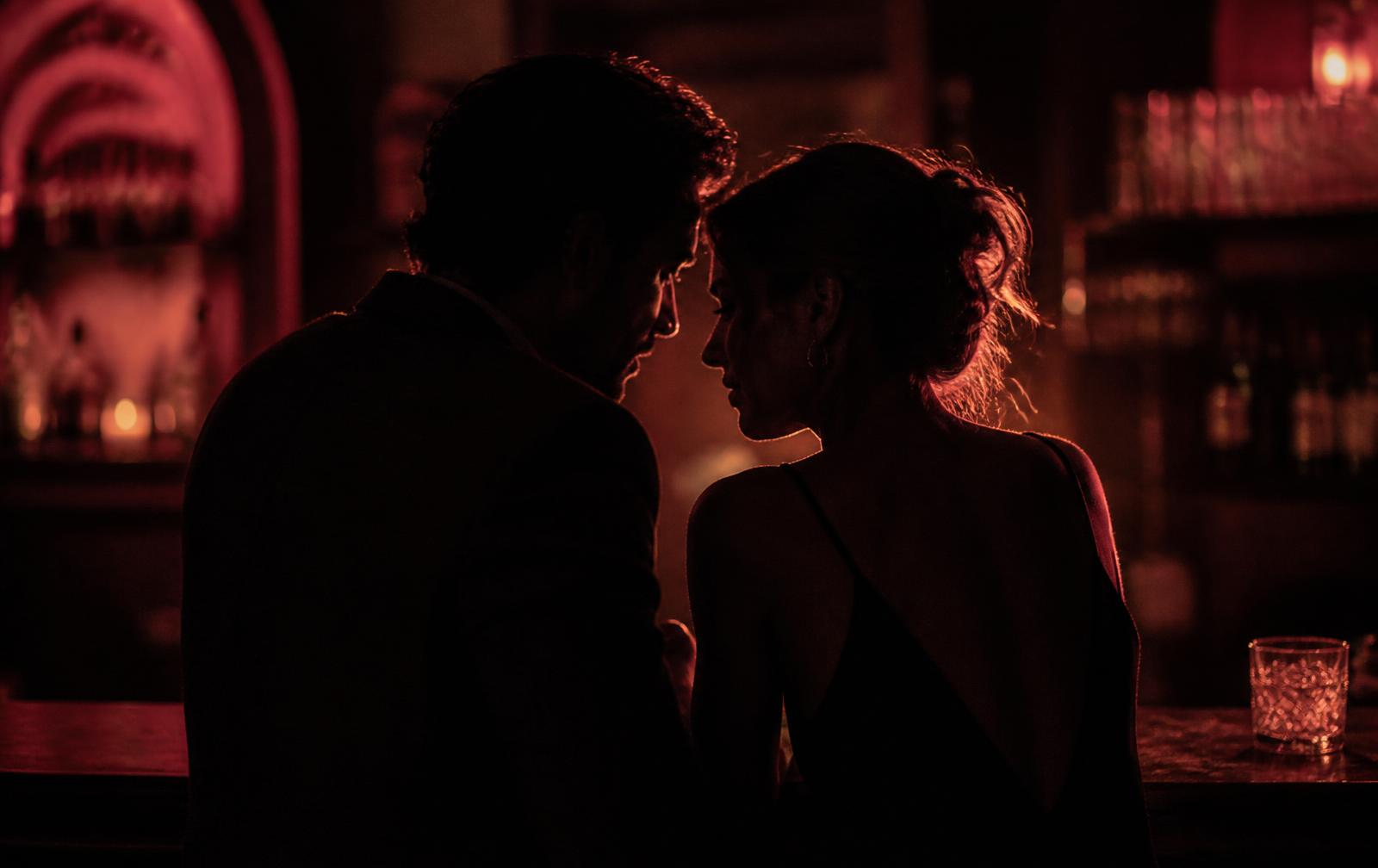 A couple talking closely in a dimly lit bar